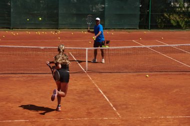 Profesyonel bir tenisçi ve onun koçu tenis kortunda güneşli bir günde antrenman yapıyorlar. Profesyonel bir tenisçinin antrenmanı ve hazırlığı.