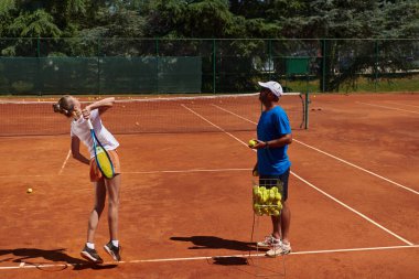 Profesyonel bir tenisçi ve onun koçu tenis kortunda güneşli bir günde antrenman yapıyorlar. Profesyonel bir tenisçinin antrenmanı ve hazırlığı.
