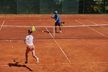 Profesyonel bir tenisçi ve onun koçu tenis kortunda güneşli bir günde antrenman yapıyorlar. Profesyonel bir tenisçinin antrenmanı ve hazırlığı.