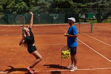 Profesyonel bir tenisçi ve onun koçu tenis kortunda güneşli bir günde antrenman yapıyorlar. Profesyonel bir tenisçinin antrenmanı ve hazırlığı.
