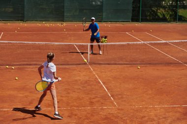 Profesyonel bir tenisçi ve onun koçu tenis kortunda güneşli bir günde antrenman yapıyorlar. Profesyonel bir tenisçinin antrenmanı ve hazırlığı.