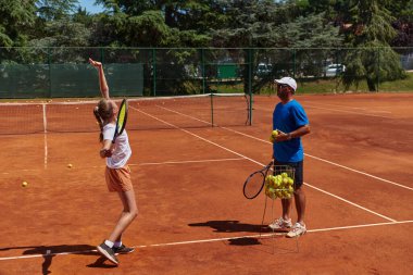 Profesyonel bir tenisçi ve onun koçu tenis kortunda güneşli bir günde antrenman yapıyorlar. Profesyonel bir tenisçinin antrenmanı ve hazırlığı.