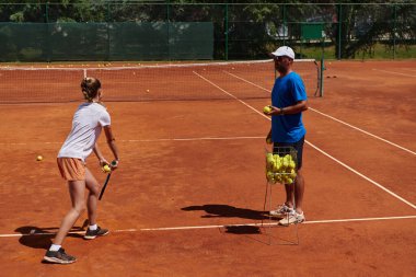 Profesyonel bir tenisçi ve onun koçu tenis kortunda güneşli bir günde antrenman yapıyorlar. Profesyonel bir tenisçinin antrenmanı ve hazırlığı.