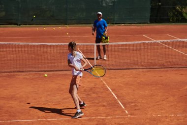 Profesyonel bir tenisçi ve onun koçu tenis kortunda güneşli bir günde antrenman yapıyorlar. Profesyonel bir tenisçinin antrenmanı ve hazırlığı.