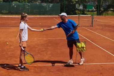 Profesyonel bir tenisçi ve onun koçu tenis kortunda güneşli bir günde antrenman yapıyorlar. Profesyonel bir tenisçinin antrenmanı ve hazırlığı.