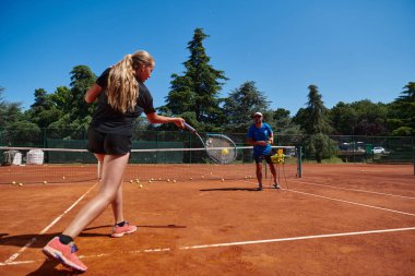 Profesyonel bir tenisçi ve onun koçu tenis kortunda güneşli bir günde antrenman yapıyorlar. Profesyonel bir tenisçinin antrenmanı ve hazırlığı.