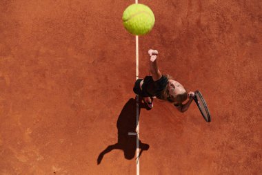 Profesyonel bir bayan tenisçinin üst görüntüsü tenis topunu sahada hassas ve güçlü bir şekilde servis eder.. 