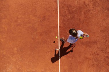 Profesyonel bir bayan tenisçinin üst görüntüsü tenis topunu sahada hassas ve güçlü bir şekilde servis eder.. 