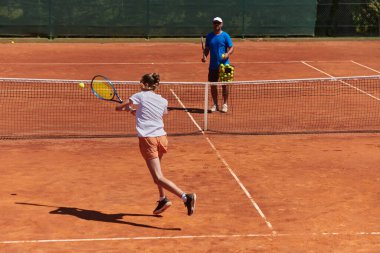 Profesyonel bir tenisçi ve onun koçu tenis kortunda güneşli bir günde antrenman yapıyorlar. Profesyonel bir tenisçinin antrenmanı ve hazırlığı.