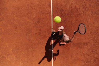 Profesyonel bir tenisçinin üst görüntüsü, tenis topunu hassas ve güçlü bir şekilde sahada servis eder.. 