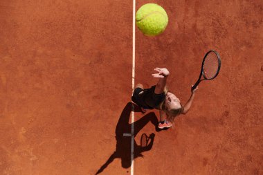 Profesyonel bir bayan tenisçinin üst görüntüsü tenis topunu sahada hassas ve güçlü bir şekilde servis eder.. 