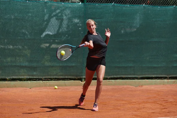 在阳光灿烂的日子里 一个年轻姑娘在一场比赛中表现出了专业的网球技巧 四周环绕着现代网球场的美感 — 图库照片