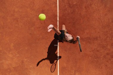 Profesyonel bir bayan tenisçinin üst görüntüsü tenis topunu sahada hassas ve güçlü bir şekilde servis eder.. 