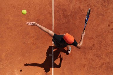 Profesyonel bir tenisçinin üst görüntüsü, tenis topunu hassas ve güçlü bir şekilde sahada servis eder.. 