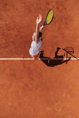 Profesyonel bir bayan tenisçinin üst görüntüsü tenis topunu sahada hassas ve güçlü bir şekilde servis eder.. 