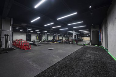 Çeşitli ekipmanlara sahip boş bir modern spor salonu, geniş, işlevsel ve iyi donanımlı bir eğitim tesisi sunuyor..