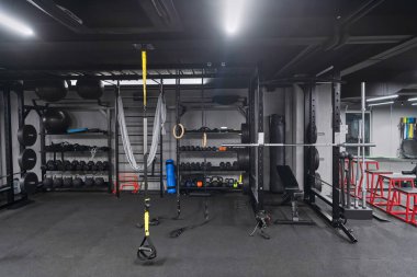 Çeşitli ekipmanlara sahip boş bir modern spor salonu, geniş, işlevsel ve iyi donanımlı bir eğitim tesisi sunuyor..