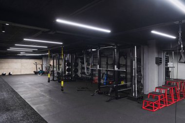 Çeşitli ekipmanlara sahip boş bir modern spor salonu, geniş, işlevsel ve iyi donanımlı bir eğitim tesisi sunuyor..