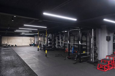 Çeşitli ekipmanlara sahip boş bir modern spor salonu, geniş, işlevsel ve iyi donanımlı bir eğitim tesisi sunuyor..