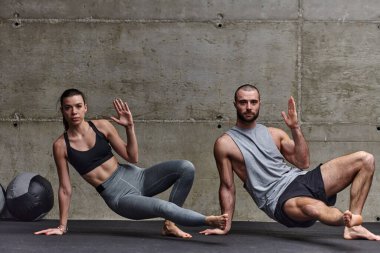 Spor salonunda birlikte esneme egzersizleri yapan çekici bir çift fitness, esneklik ve genel refahı için kendilerini adadıklarını gösteriyorlar. Senkronize hareketlerle...