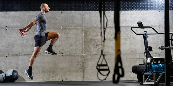 健美男子在跳进现代体育馆时在空气中被抓住的肌肉发达的男子 他通过一项高强度的健身项目展示了自己的运动能力 力量和决心 — 图库照片
