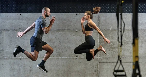 現代のジムでさまざまな種類のジャンプを練習し 運動能力を証明するフィットカップル — ストック写真