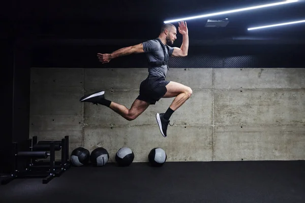 Muskulös Man Fångas Luften När Han Hoppar Ett Modernt Gym — Stockfoto