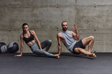 Spor salonunda birlikte esneme egzersizleri yapan çekici bir çift fitness, esneklik ve genel refahı için kendilerini adadıklarını gösteriyorlar. Senkronize hareketlerle...
