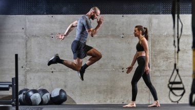 Modern bir spor salonunda çeşitli atlama sporları yapan fit bir çift fiziksel uygunluklarını, güçlerini ve atletik performanslarını gösteriyor..