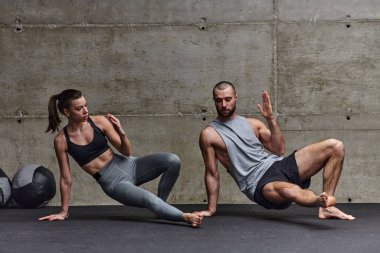 Spor salonunda birlikte esneme egzersizleri yapan çekici bir çift fitness, esneklik ve genel refahı için kendilerini adadıklarını gösteriyorlar. Senkronize hareketlerle...