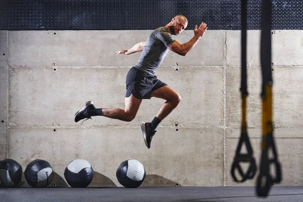 Hombre Musculoso Capturado Aire Mientras Salta Gimnasio Moderno Mostrando Atletismo —  Fotos de Stock