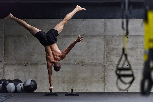 立ち位置に筋肉の男 現代のジムで彼の全体的な体の安定性と強さを向上させるために様々な演習を実行しながら 彼の優れたバランスと体の制御を紹介します — ストック写真