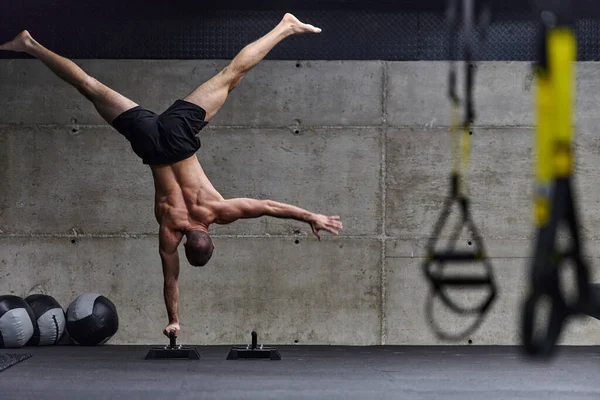 体操运动员手倒立的肌肉男 在现代体育馆进行各种运动以提高身体的整体稳定性和力量时 表现出异常的平衡和对身体的控制 — 图库照片