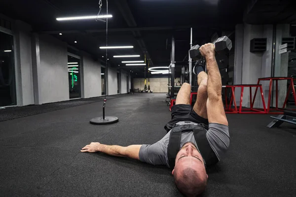 근육질의 남자가 현대적 체육관에서 덤벨을 가지고 운동하는 초점을 맞추고 — 스톡 사진