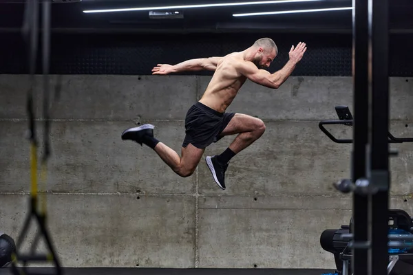 Muskulös Man Fångas Luften När Han Hoppar Ett Modernt Gym — Stockfoto