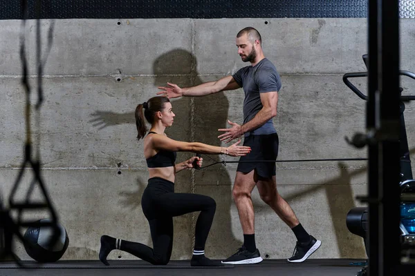 Een Gespierde Man Assisteert Een Fitte Vrouw Een Moderne Fitnessruimte — Stockfoto