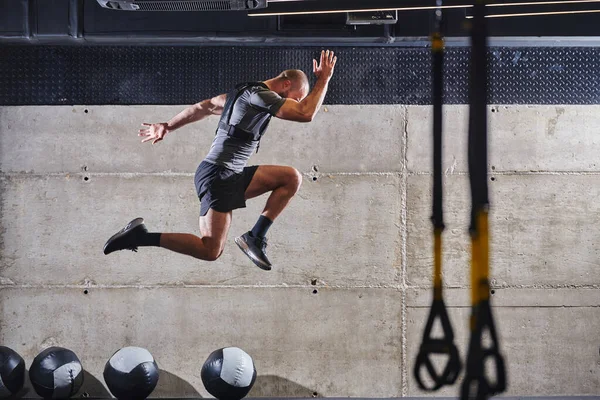 현대적 체육관에서 점프를 하다가 공중에 근육질의 남자가고 관련된 일과를 자신의 — 스톡 사진