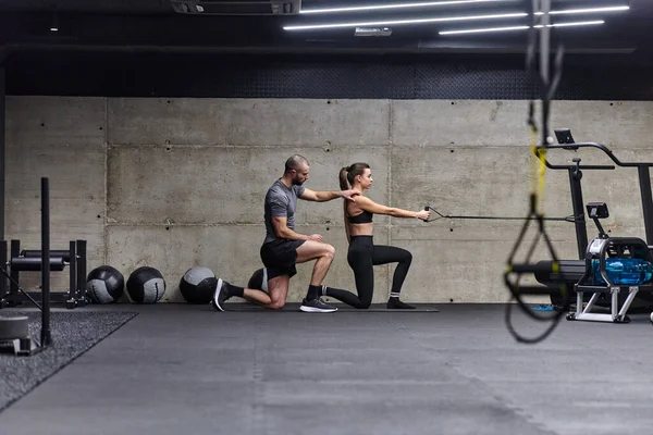 Een Gespierde Man Assisteert Een Fitte Vrouw Een Moderne Fitnessruimte — Stockfoto