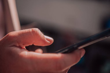 İş adamının yakın plan fotoğrafı, akıllı telefonunu açık havada kullanır ve modern profesyonel hayatta teknolojinin ve hareketliliğin kusursuz bütünlüğünü gösterir.
