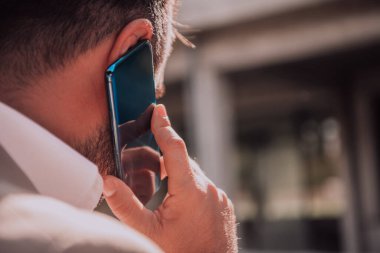 Akıllı telefonunu açık havada kullanan bir işadamı modern profesyonel hayatta teknolojinin ve hareketliliğin kusursuz bütünlüğünü sergiliyor.