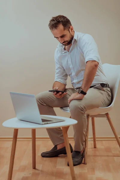 Empresário Confiante Sentado Usando Laptop Smartphone Com Uma Expressão Determinada — Fotografia de Stock