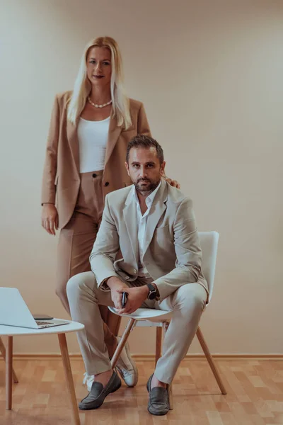 ビジネスカップルはベージュを背景に一緒に写真をポーズし 彼らの専門的なパートナーシップをキャプチャし 団結と成功の時代を超越したイメージを作成します — ストック写真