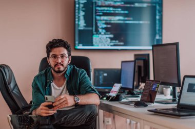 Bir programcı ofisinde otururken akıllı telefon uygulamalarını özenle test ediyor. Yüksek kalite fotoğraf