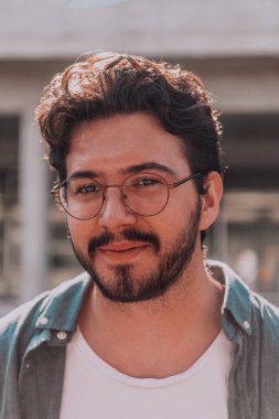 Modern bir adamın portresi, kendine güveni ve stili, açık bir arkaplanda, karizmasını ve modaya uygun tavırlarını sergiliyor.