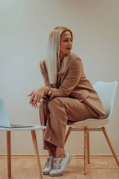 Profesionální Podnikatelka Sedí Židli Obklopená Klidným Béžovým Pozadím Pilně Pracuje — Stock fotografie
