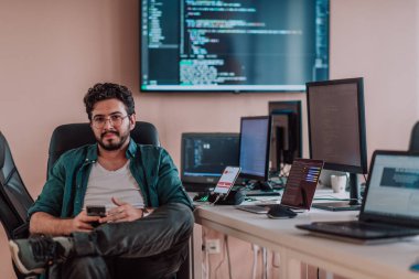 Bir programcı ofisinde otururken akıllı telefon uygulamalarını özenle test ediyor. Yüksek kalite fotoğraf