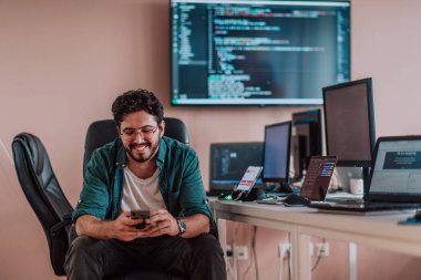 Bir programcı ofisinde otururken akıllı telefon uygulamalarını özenle test ediyor. Yüksek kalite fotoğraf