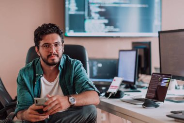 Bir programcı ofisinde otururken akıllı telefon uygulamalarını özenle test ediyor. Yüksek kalite fotoğraf
