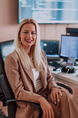 Bilgisayarlarla çevrili bir programcı ofisinde oturan bir iş kadını uzmanlığını ve teknolojiye olan bağlılığını gösteriyor.