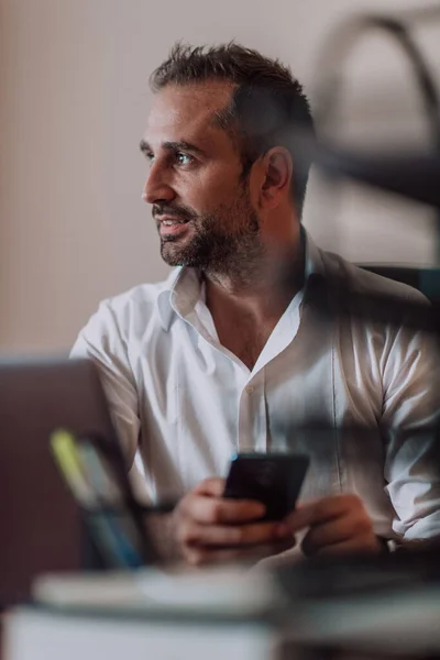 一位商人坐在办公室里用智能手机展示他的职业举止和积极的交流 — 图库照片